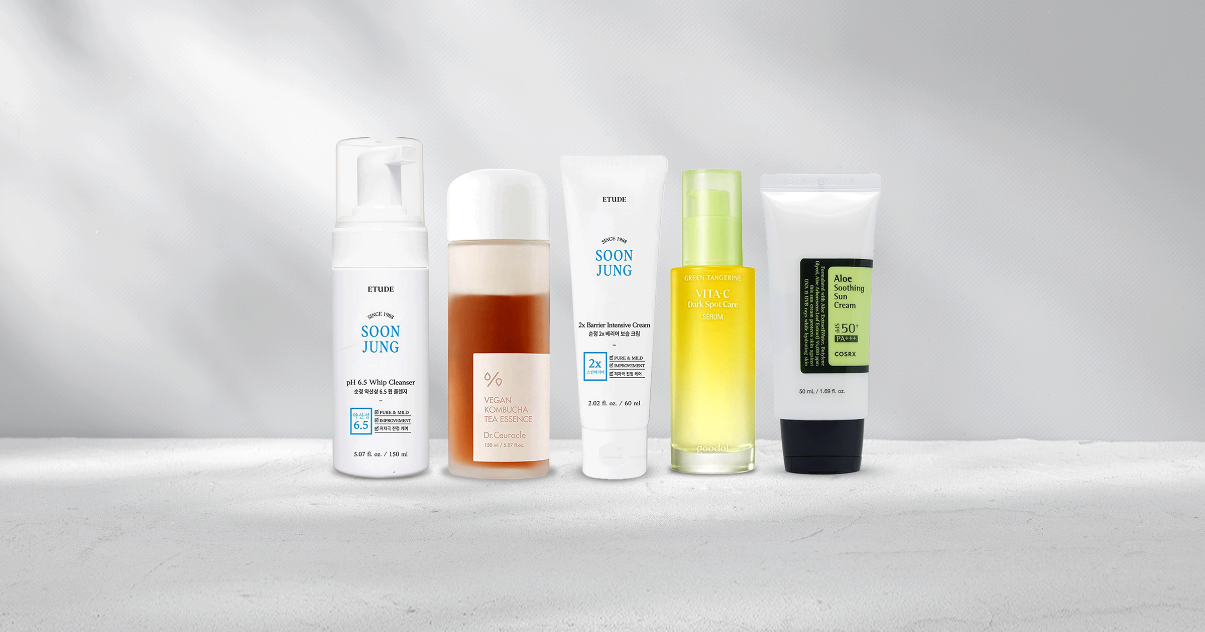 Skincare products including cleanser, toner, serum, moisturizer, and suncare standing next to each other.