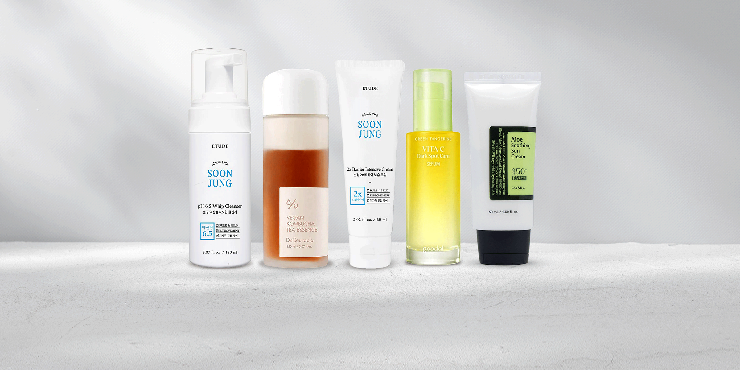 Skincare products including cleanser, toner, serum, moisturizer, and suncare standing next to each other.